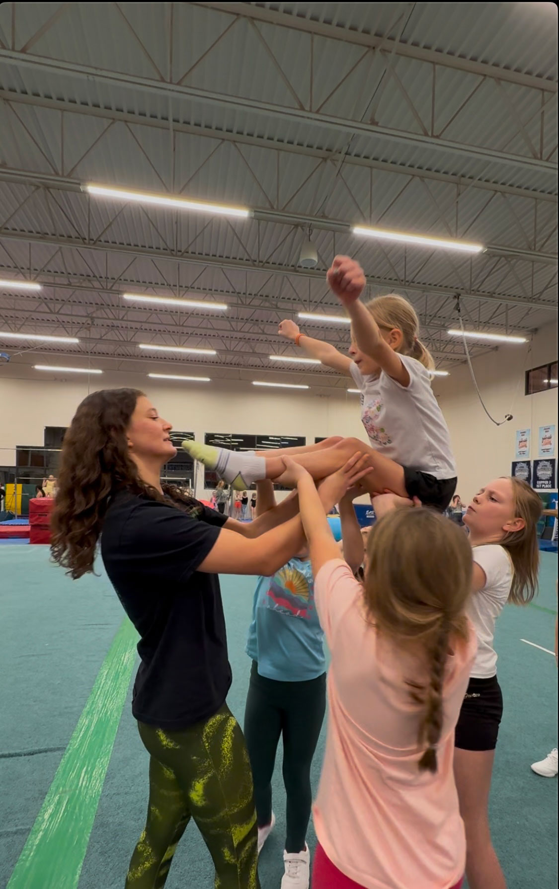 Cheer coach spotting kids with a cheerleading lift 