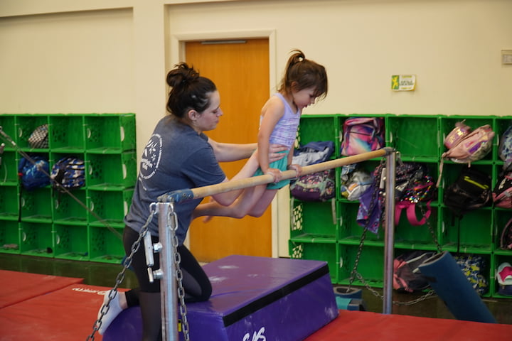 teacher helping girl on bars