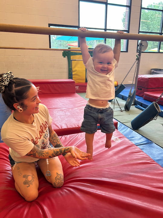 mom and toddler on bars in gym